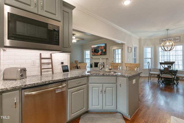 kitchen featuring appliances with stainless steel finishes, gray cabinets, a sink, and a peninsula