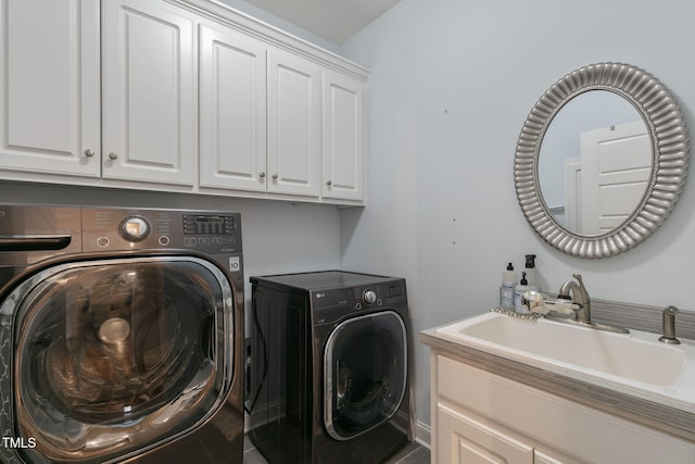 clothes washing area with washing machine and dryer, cabinet space, and a sink