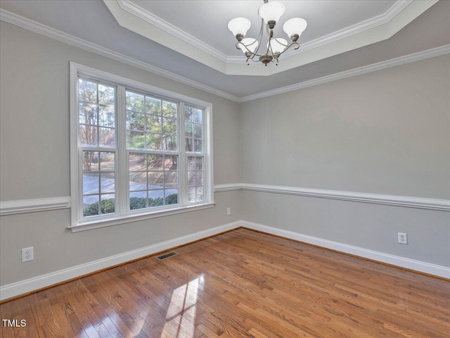 unfurnished room featuring visible vents, baseboards, a chandelier, hardwood / wood-style flooring, and a raised ceiling