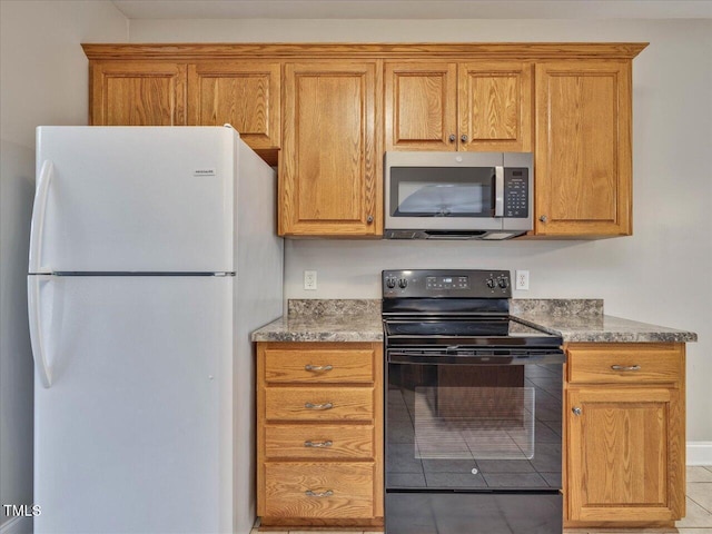 kitchen with stainless steel microwave, brown cabinets, electric range, and freestanding refrigerator