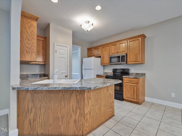 kitchen featuring black electric range oven, stainless steel microwave, freestanding refrigerator, a peninsula, and light tile patterned flooring