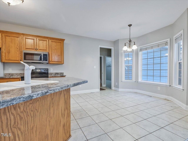 kitchen with stainless steel microwave, black range with electric cooktop, baseboards, brown cabinets, and hanging light fixtures