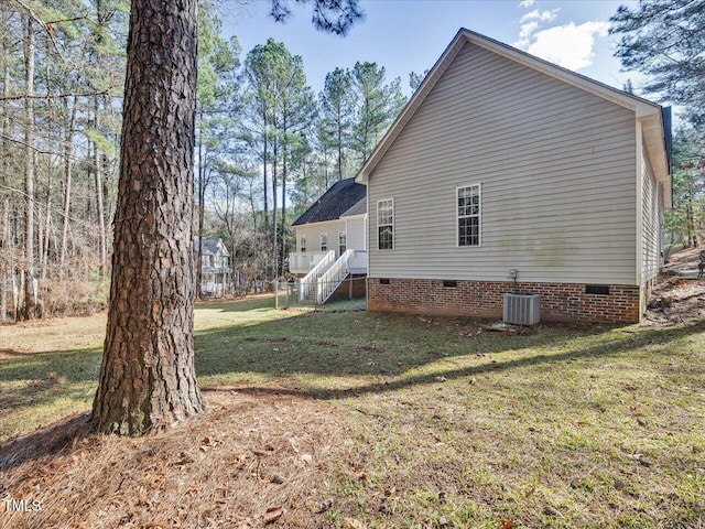 view of side of home featuring a yard, central AC unit, and crawl space