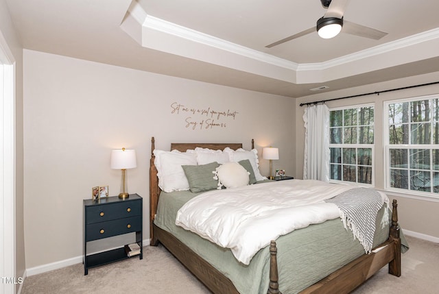 bedroom featuring ornamental molding, a raised ceiling, light carpet, and baseboards