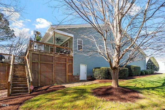 back of property with a deck, a yard, stairway, and a ceiling fan