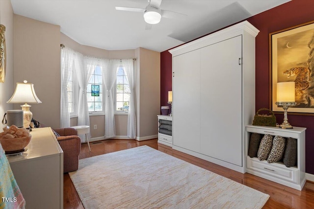 bedroom with a ceiling fan, a closet, baseboards, and wood finished floors