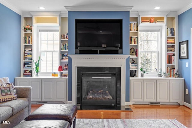 living room featuring light wood finished floors, ornamental molding, and a wealth of natural light