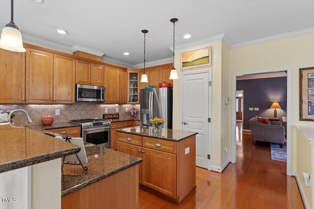 kitchen with glass insert cabinets, appliances with stainless steel finishes, brown cabinets, and dark stone countertops