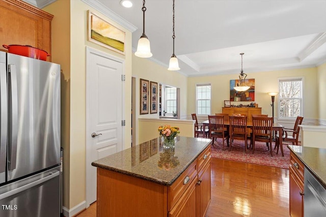 kitchen with appliances with stainless steel finishes, a tray ceiling, brown cabinetry, and crown molding