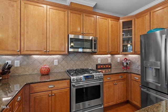 kitchen with dark stone counters, stainless steel appliances, brown cabinetry, and glass insert cabinets