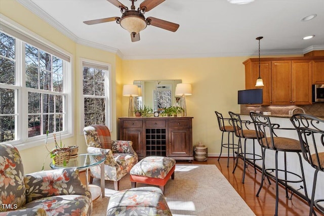 interior space featuring ornamental molding, wood finished floors, a ceiling fan, and baseboards