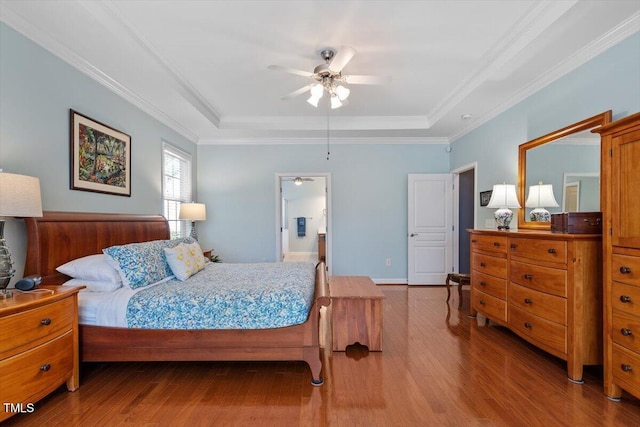 bedroom with ornamental molding, a raised ceiling, and wood finished floors