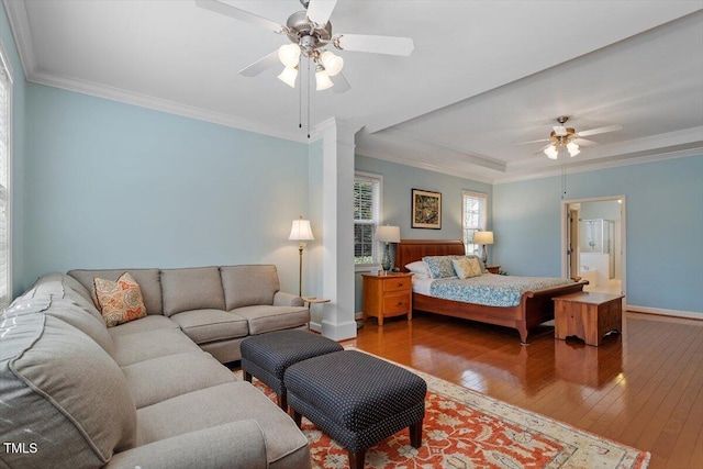 bedroom with wood-type flooring, crown molding, baseboards, and decorative columns