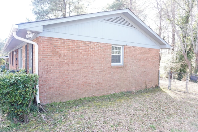 view of property exterior featuring a gate, brick siding, and fence