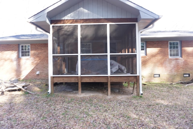 back of property with crawl space, a sunroom, and brick siding