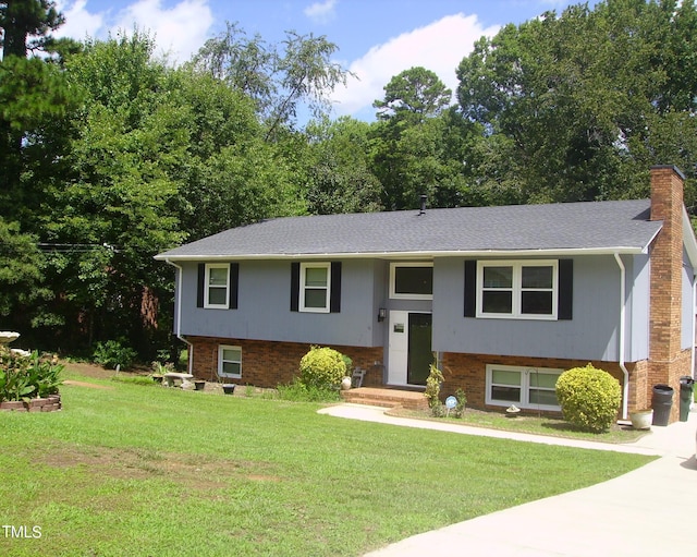 bi-level home featuring a front lawn, a chimney, and brick siding