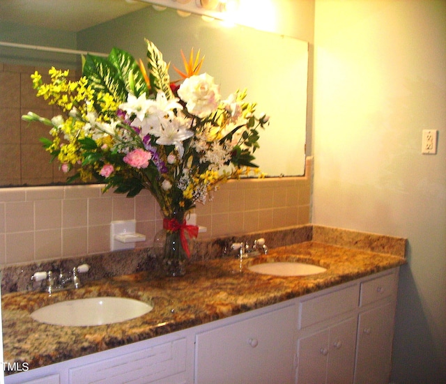 bathroom featuring double vanity, decorative backsplash, and a sink