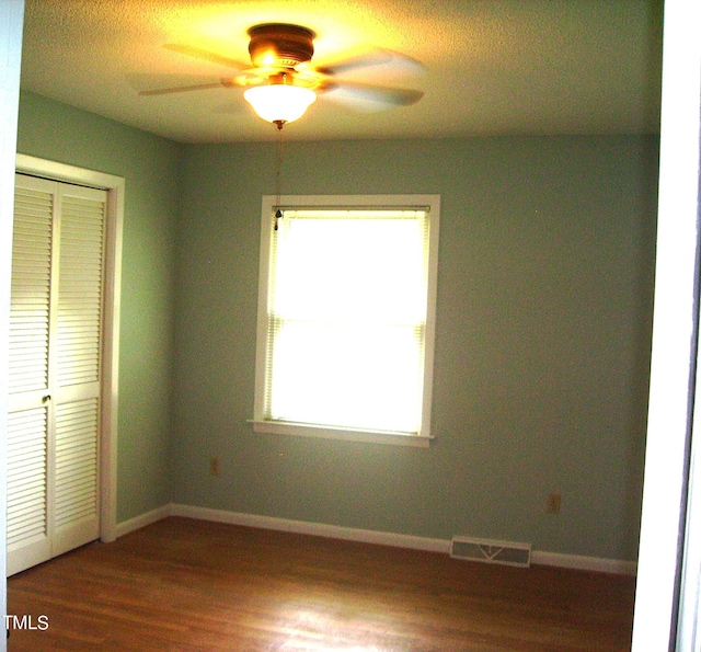 unfurnished bedroom with a closet, visible vents, baseboards, and wood finished floors