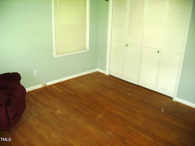 unfurnished bedroom with a closet, wood finished floors, and baseboards