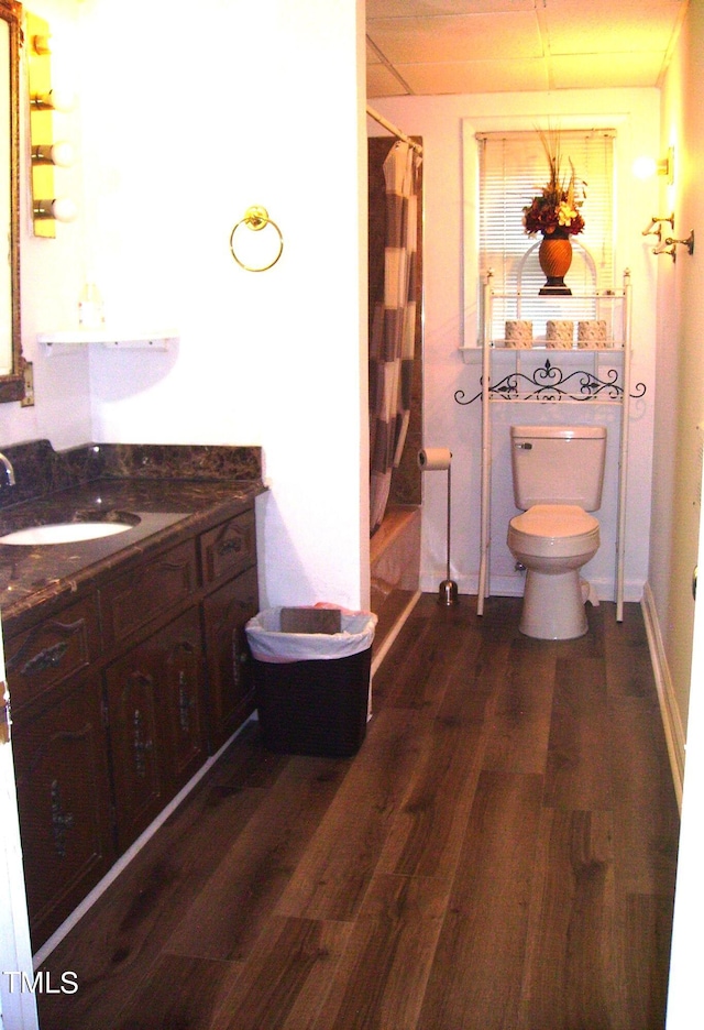 bathroom with toilet, shower / bath combo with shower curtain, wood finished floors, and vanity