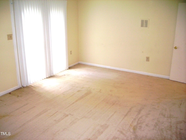 empty room with light wood-style flooring, visible vents, and baseboards