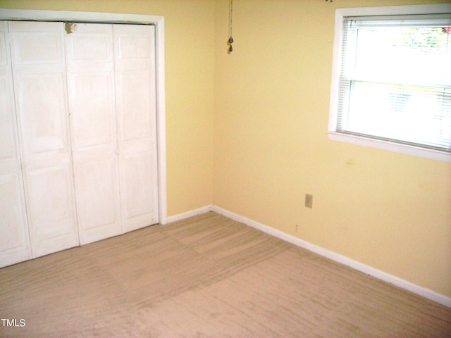 unfurnished bedroom with light wood-style floors, a closet, multiple windows, and baseboards