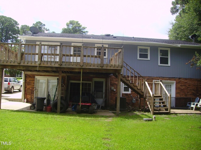 back of property with brick siding, a yard, stairway, a wooden deck, and a patio area