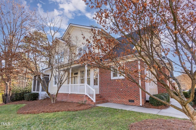 view of front of home with crawl space, covered porch, a front lawn, and brick siding