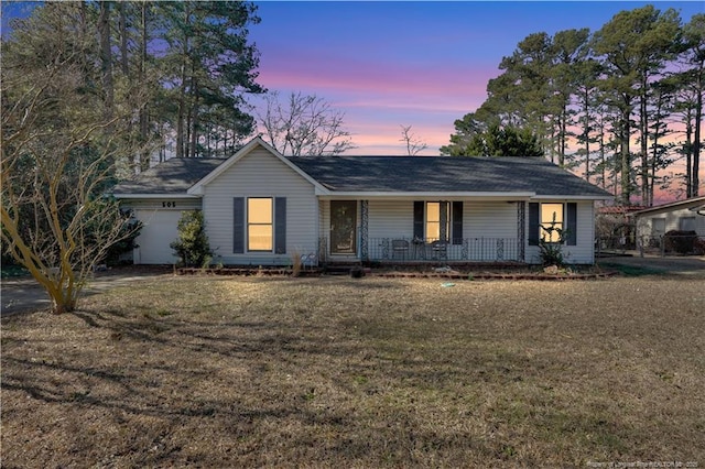 single story home with an attached garage, covered porch, and a yard