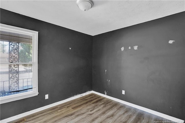 unfurnished room featuring visible vents, baseboards, and wood finished floors