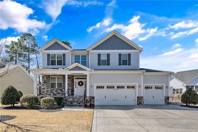 craftsman house with a garage, covered porch, stone siding, and concrete driveway