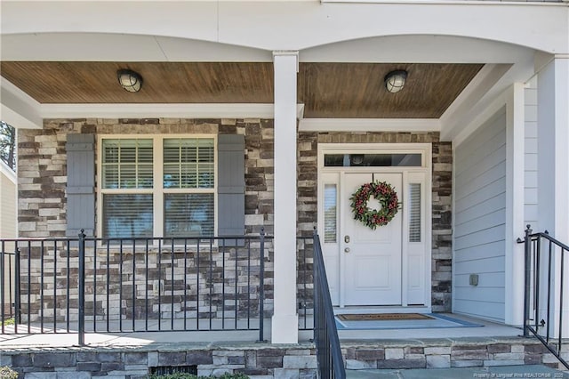 doorway to property featuring a porch and stone siding