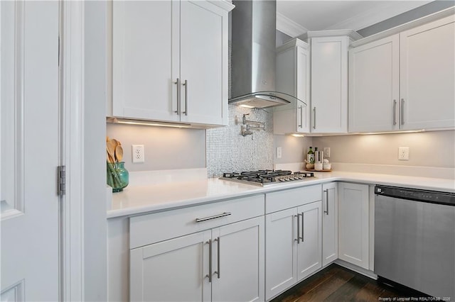 kitchen with light countertops, appliances with stainless steel finishes, wall chimney range hood, and white cabinetry