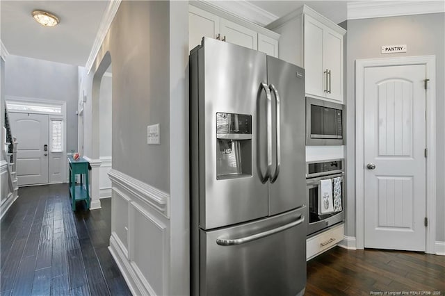 kitchen featuring dark wood-style floors, a wainscoted wall, crown molding, appliances with stainless steel finishes, and white cabinets