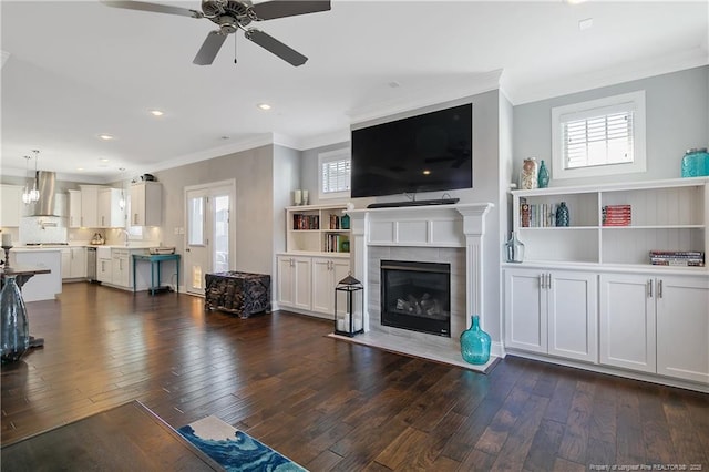 living area featuring dark wood-style flooring, a fireplace, and crown molding