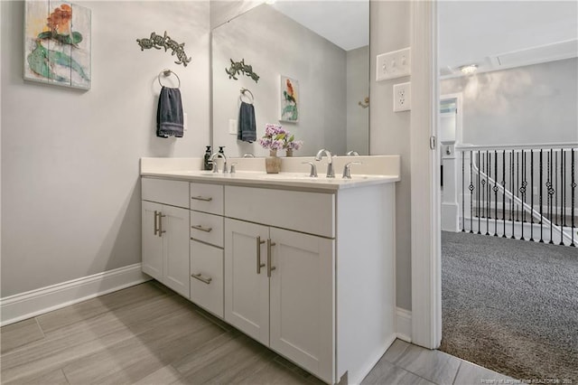 full bath with double vanity, wood finished floors, a sink, and baseboards