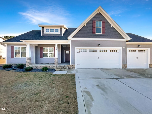 craftsman-style house with a garage, covered porch, concrete driveway, and a front yard