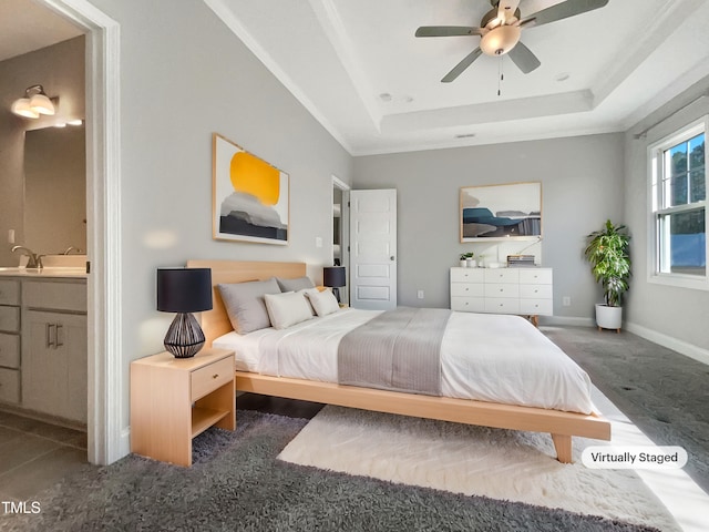 carpeted bedroom with baseboards, a raised ceiling, connected bathroom, ceiling fan, and a sink