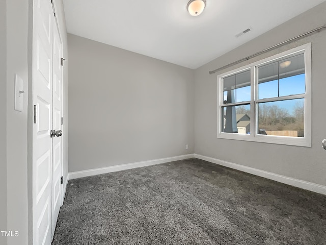 unfurnished room featuring visible vents, dark carpet, and baseboards