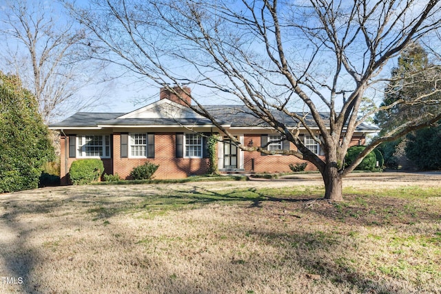 single story home with brick siding, a chimney, and a front yard