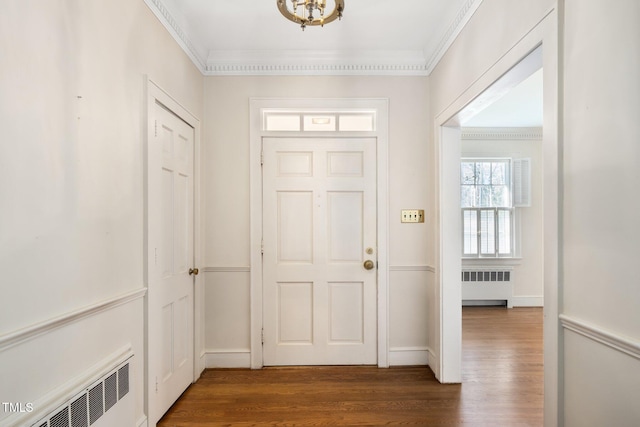 foyer entrance featuring baseboards, crown molding, radiator heating unit, and wood finished floors