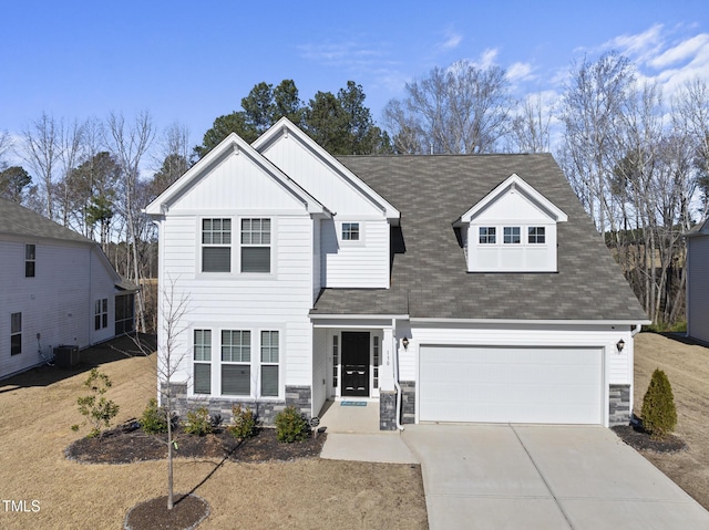 view of front of house with board and batten siding, concrete driveway, stone siding, and central AC