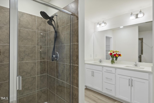 bathroom featuring double vanity, a shower stall, and a sink