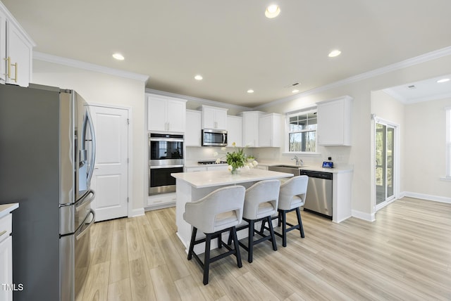 kitchen featuring a kitchen island, a sink, stainless steel appliances, white cabinets, and a kitchen breakfast bar