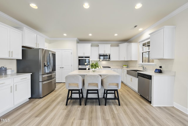 kitchen with a sink, a breakfast bar, white cabinetry, and stainless steel appliances