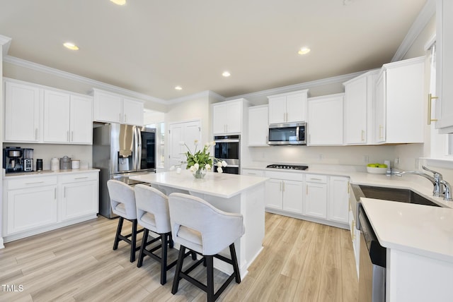 kitchen with white cabinets, appliances with stainless steel finishes, crown molding, and a kitchen breakfast bar