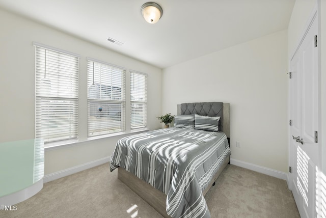 carpeted bedroom featuring a closet, visible vents, and baseboards