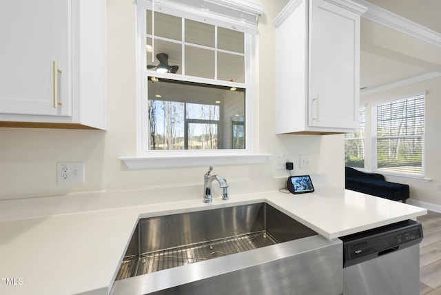 kitchen featuring white cabinetry, a sink, light countertops, stainless steel dishwasher, and crown molding