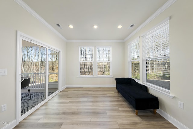 living area featuring baseboards, light wood-style floors, visible vents, and ornamental molding