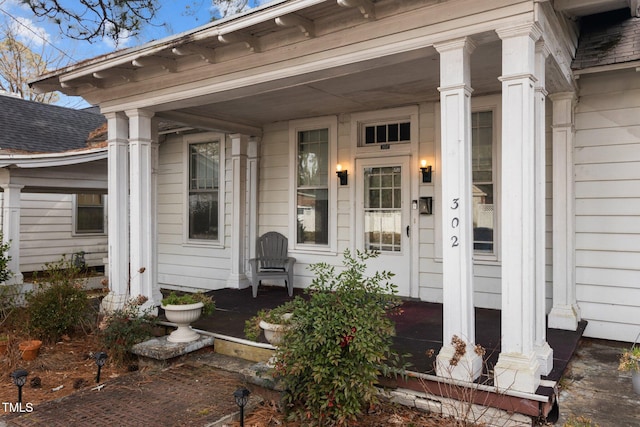 entrance to property featuring a shingled roof and a porch